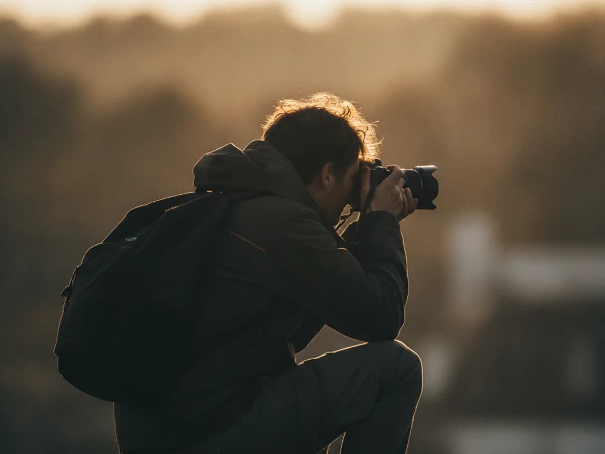 Fotograf im Gegenlicht bei der Arbeit, von hinten aufgenommen